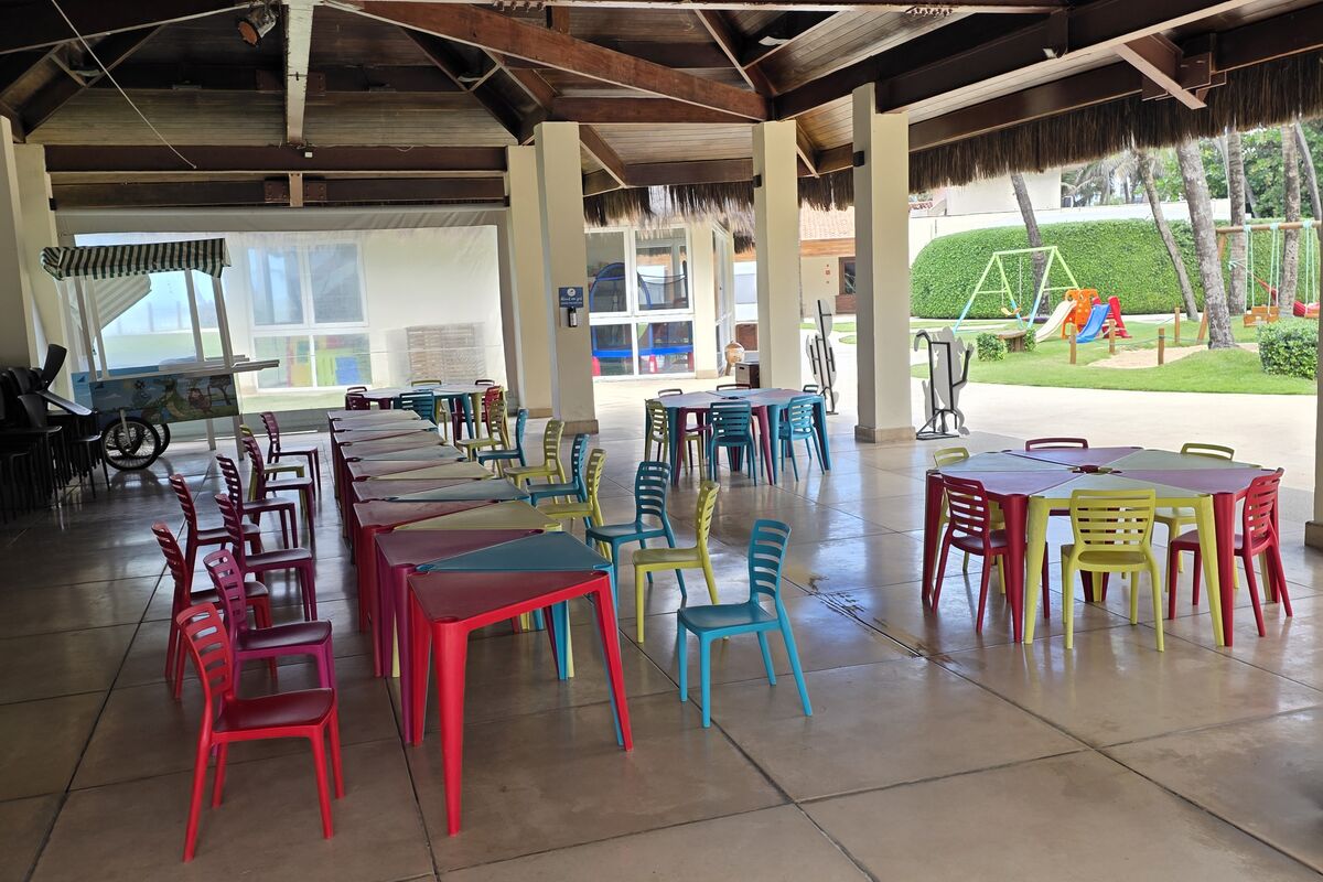 Espaço de oficinas do Clubinho do Jacaré, com mesas e cadeiras infantis coloridas, sem pessoas.