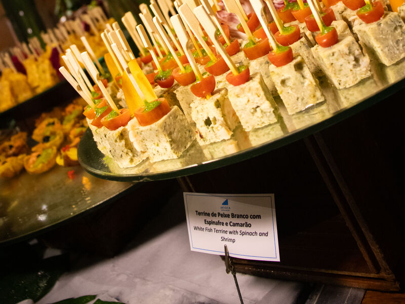 Fileira de espetinhos e canapés servidos em travessa.